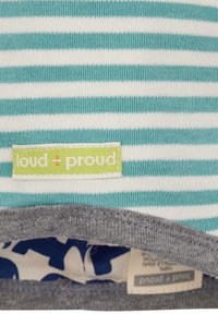 Maglietta a righe con strisce orizzontali turchesi e bianche. Collo grigio. Presenta un'etichetta verde con la scritta "loud + proud" cucita.