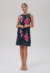 Dunkelblauses ärmelloses Kleid mit großen pinken Orchideen-Mustern, glattes Material mit sanftem Fall, knielang mit asymmetrischem Saumdetail.