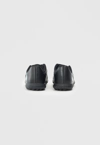 Baskets de sport noires avec un dessus synthétique lisse, présentant un talon texturé, une semelle flexible et un minimum de marquage.