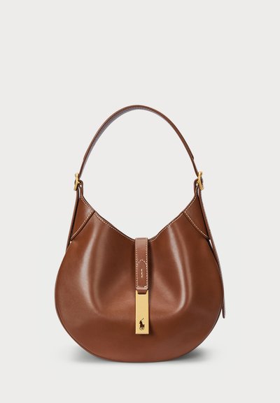 Ruda odinė hobo rankinė su lenkta forma, viena rankena, auksinės spalvos detalės ir centrinis diržas su logotipo akcentu.