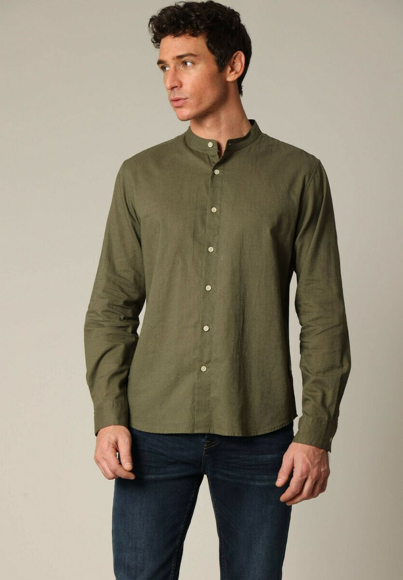 Olijfgroene blouse met lange mouwen en een opstaande kraag, met een knoopsluiting aan de voorkant en een relaxte pasvorm, gemaakt van een textuurstof.