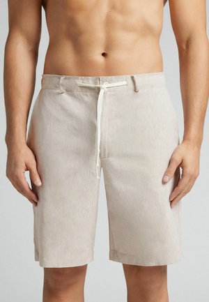 Pantaloni corti in lino beige con chiusura a coulisse, caratterizzati da una vestibilità rilassata e una superficie testurizzata. L'orlo arriva appena sopra il ginocchio.