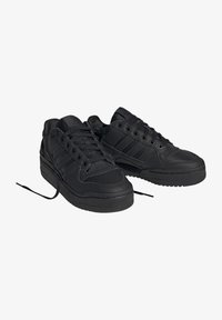 Svarta sneakers i slät läder med perforerade detaljer, med en tjock sula, svarta snören och tre distinkta ränder på sidan.