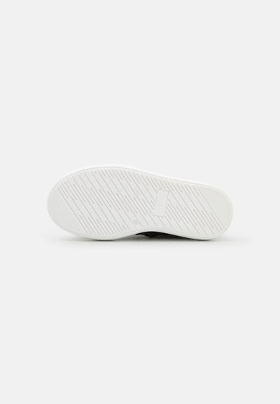 Sola de sapato atlético preta com um fundo de borracha branca texturizada; apresenta um piso com padrão para aderência e uma área para rótulo na lateral.