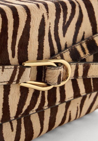 Τσάντα με υφή ριγέ ζέβρας και χρυσή μεταλλική αγκράφα σε δερμάτινο λουρί.