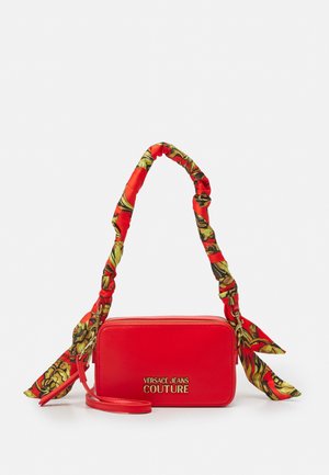 Czerwona prostokątna torebka na ramię z złotym logo "Versace Jeans Couture", z uchwytem owiniętym materiałem w kwiatowy wzór oraz odpinanym paskiem.