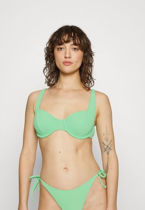 Πράσινο μπικίνι σετ που διαθέτει υφασμάτινη μπλούζα με στήριξη και φαρδιές τιράντες, καθώς και χαμηλής μέσης σλιπ με κορδόνια στο πλάι.