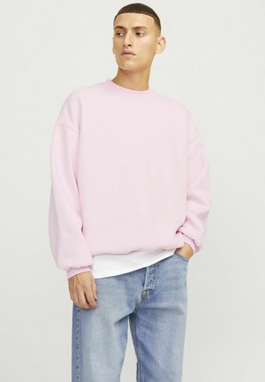 Lyserød sweatshirt med rund halsudskæring og sænkede skuldre, parret med lyseblå denimjeans. Blød tekstur, afslappet pasform.