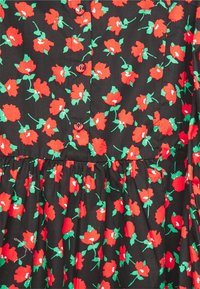 Vestido preto com flores vermelhas e folhas verdes, apresentando fechos de botão e uma bainha em camadas com babados. Feito de tecido leve.