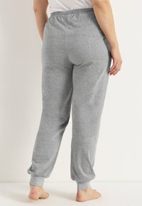 Graue Jogginghosen mit einem elastischen Bund und gerippten Knöcheln, aus weichem Material, mit einem schlichten Design ohne sichtbare Muster.