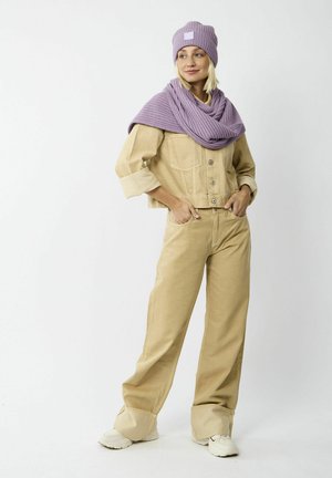 Beige Jeansjacke mit Knöpfen und aufgekrempelten Ärmeln, passenden beigen weit geschnittenen Hosen, lila gestricktem Schal und lila Mütze, alles aus strukturierten Materialien.