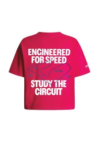 Červené tričko s bielym textom "Navrhnuté pre rýchlosť" a "Študuj okruh" obklopujúcim schému pretekárskej trate Veľkej ceny Rakúska.