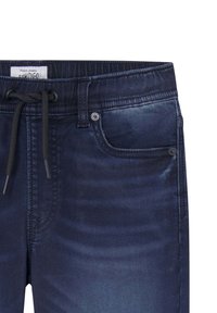 Jeans de mezclilla de color índigo oscuro, con una cintura con cordón, costuras en contraste y un bolsillo frontal con un detalle de botón de metal.