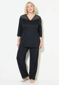 Schwarzes Pyjama-Set mit einem V-Ausschnitt-Top mit Spitzenverzierungen und Dreiviertelärmeln, kombiniert mit passenden Hosen, die ebenfalls mit Spitze verziert sind.