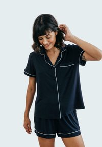Conjunto de pijama azul marino hecho de tejido suave, que incluye una camisa de botones de manga corta con ribetes blancos en contraste y pantalones cortos a juego.