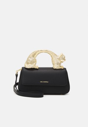 Black leather handbag featuring a gold cat-shaped handle and adjustable strap, with a magnetic closure and subtle logo detail.