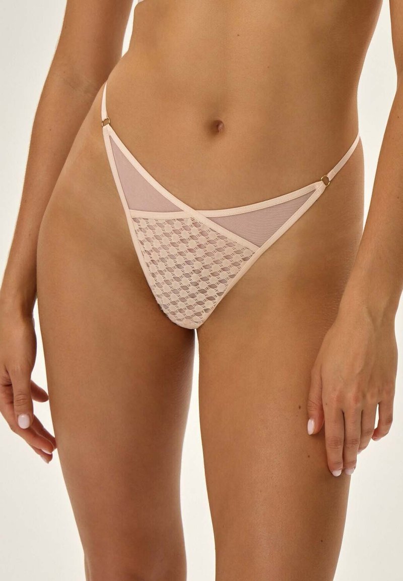 Koronkowy bikini z przezroczystymi panelami, w jasnoróżowym kolorze, w geometryczny wzór, z cienkimi ramiączkami i złotymi akcentami.