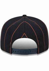 Schwarze Kappe mit orangefarbenen Nähten, verstellbarem Kunststoffverschluss auf der Rückseite und einem strukturierten Design. Glatte Textur mit runder Form.