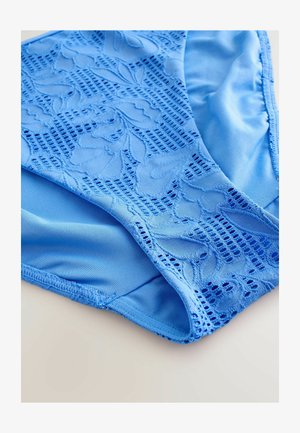 Vaaleansininen bikinitoppi, jossa on kukkakuvioinen pitsikuvio, sileä kangasrakennus ja yhdistetty muotoilu, joka korostaa mattapintaista viimeistelyä.