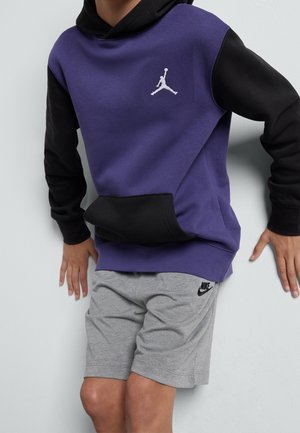Hættetrøje i lilla og sort med frontlomme og hvidt Jordan-logo; kombineret med grå shorts med sort Nike-logo.