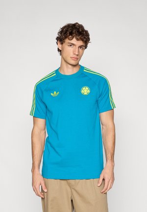 Jasnoniebieska bawełniana koszulka z żółtymi akcentami, z okrągłym dekoltem, trzema paskami na ramionach i okrągłym logo na piersi.