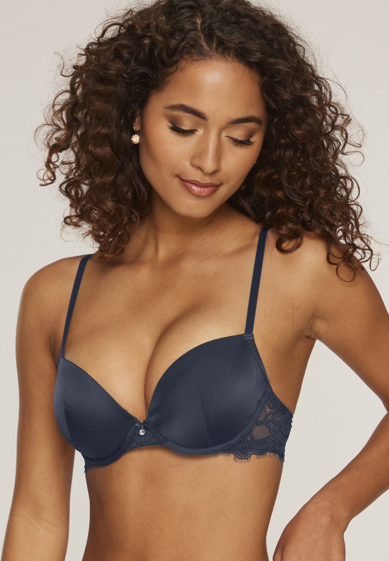 Navyblauwe gewatteerde beha met kantdetail, slanke verstelbare bandjes en een kleine edelsteenaccent in het midden. Gladde textuur en gevormde vorm.