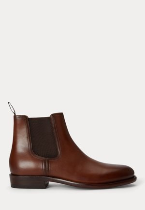 Botte Chelsea en cuir marron avec panneau latéral élastique noir et petit talon empilé sur fond blanc.