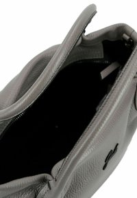 Graue Lederhandtasche mit strukturiertem Finish, ausgestattet mit einem Reißverschluss und einem schwarzen Innenraum. Ein einzelner Griff oben für einfaches Tragen.