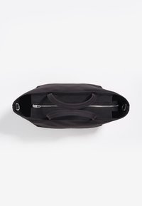 Czarna torba na ramię z płótna, z dwoma górnymi uchwytami, zamknięciem na zamek i wewnętrzną kieszenią. Charakterystyczne przeszycia i gładka faktura.