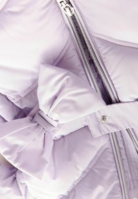 Giacca imbottita di un leggero color lavanda con finitura satinata. Presenta un dettaglio a fiocco sul lato, zip argentata e texture trapuntata.