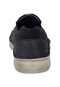 Zapato de piel azul marino con una textura suave, forma redondeada y suela de goma beige; cuenta con detalles de costura y un diseño de talón abierto.