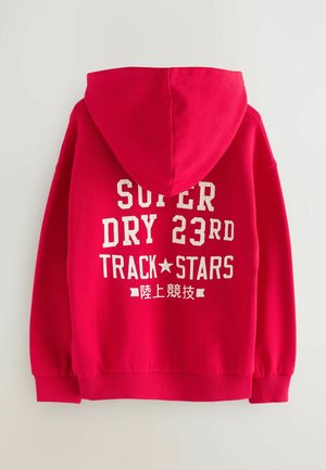 Punahuppu punamittari suurella huppulla, ribattuine hihoineen ja helmalla; takana valkoinen teksti "SUPER DRY 23RD TRACK★STARS".