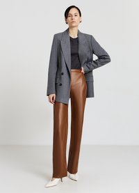 Grauer zweireihiger Blazer, dunkles Oberteil, braune weite Hose aus Kunstleder und cremefarbene spitze Pumps. Glatte Textur und maßgeschneiderte Passform.