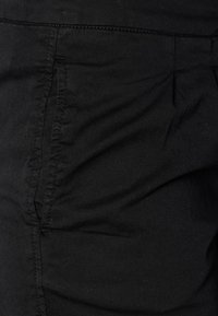 Pantalons en tissu noir avec une texture douce, présentant des coutures visibles le long des coutures et une taille lisse en haut.