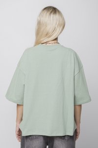 T-Shirt oversized de culoare verde deschis, cu mâneci scurte și gât rotund. Fabricat din bumbac moale, are o croială relaxată și o textură netedă.