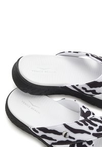 Black and white zebra print sandals with a smooth textured surface, soft footbed, and black rubber outsole. Includes “Venice Beach” logo.