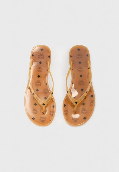 Șlapi maro transparenți cu finisaj lucios, având logo-uri MCM și modele cu diamante pe talpă și un design minimalist al baretei.