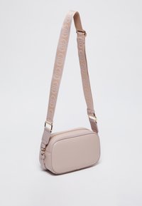Borsa a tracolla beige chiaro realizzata in pelle texture, con una tracolla a motivo geometrico e hardware dorato. Forma rettangolare slim.