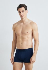 Navy blue boxer briefs made of soft fabric, featuring a black elastic waistband with "DIESEL" logo, tailored fit, and smooth texture.