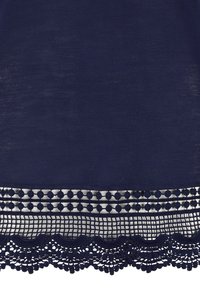 Marineblauer Stoff mit dekorativer Spitze am Saum, die kunstvolle gewellte Kanten, kleine runde Akzente und ein offenes Webdesign aufweist.