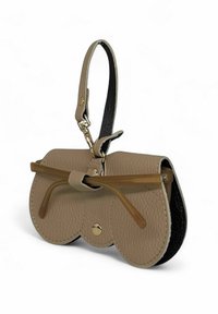 Sac à main en cuir beige avec une finition texturée, des accents noirs et une fermeture décorative en forme de nœud. Il dispose d'une poignée et de quincaillerie dorée.