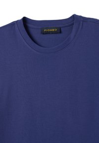 Ein schlichtes dunkelblaues T-Shirt mit Rundhalsausschnitt, das am Kragen ein schwarzes und gelbes Markenlabel mit der Aufschrift "PIOMBO" trägt.