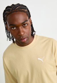 Lichtbeige sweatshirts gemaakt van zachte stof, met een ronde halslijn en een klein wit Puma-logo op de linkerkant van de borst.