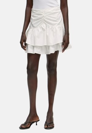 Witte gerimpelde mini-rok met geplooide details bij de taille, gemaakt van lichtgewicht stof. Gelaagde ontwerp voegt textuur en flow toe.