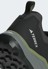 Nahaufnahme eines schwarzen und grauen Adidas Terrex Wanderschuhs an der Ferse mit strukturiertem Profilsohle und Schlaufe.