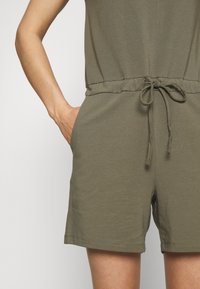 Olivgröna shorts i bomullsmix med dragsko i midjan, sidofickor och en avslappnad passform. Slät textur och knälång design.