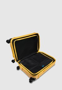 Valigia rigida gialla con interno nero, dotata di scomparto con cerniera e quattro ruote per la mobilità. Design aperto e spazioso.
