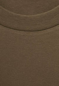 Smeđa pamučna tkanina s teksturiranim rebrastim okruglim izrezom. Materijal izgleda glatko i malo rastezljivo, s dosljednom bojom.