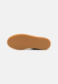 Suola di scarpa in gomma con un motivo testurizzato e rigato; colore arancione; punta rotonda; design pulito, minimal con pochi dettagli.