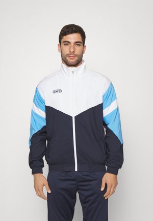 Trainingsjacke mit weißem Oberteil, marineblauem Körper und hellblauen Akzenten. Verfügt über einen hohen Kragen und einen Reißverschluss. Hergestellt aus leichtem Material.